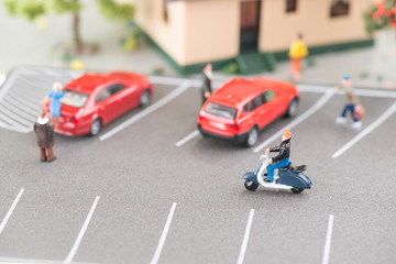 Busy street with miniature people, cars and scooter close-up