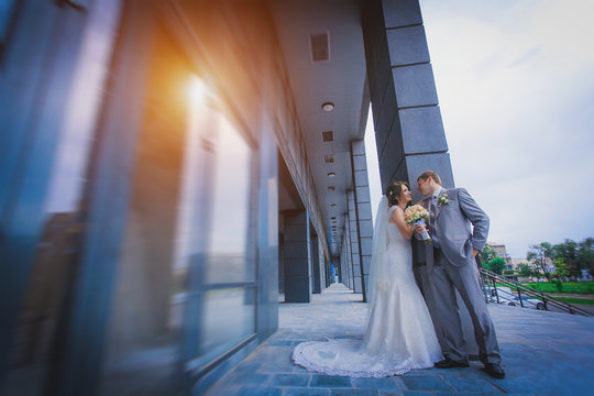 happy newlyweds against a blue modern building