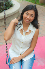 An Asian woman relaxing on a swing