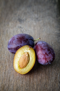 three ripe plums with leaves