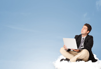 Attractive businessman sitting on cloud with copy space