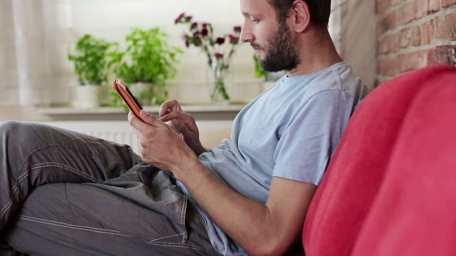 Happy young man with tablet computer sit on sofa
