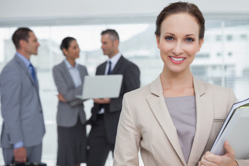 Cheerful businesswoman holding files smiling at camera