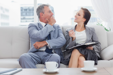 Colleagues working together sitting on sofa having coffee