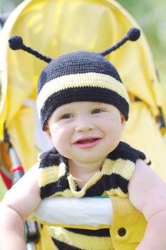 happy baby age of 10 months in bee costume on baby carriage