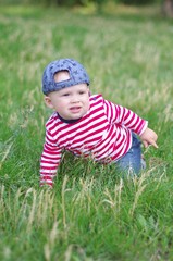 baby creeps on grass in summer