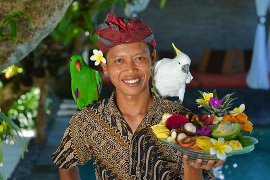 Asian waiter with a tray of tropical fruits in an exotic setting