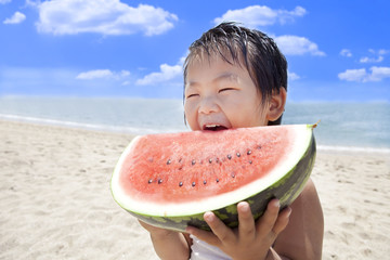 夏の海でスイカを食べる子供