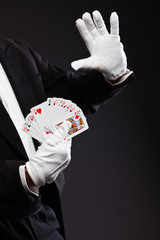 Hands of magician holding cards. Wearing black suit. Studio shot