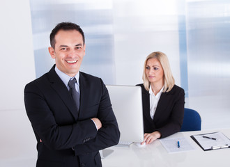 Fototapeta premium Businessman Standing In Front Of His Colleague Using Computer