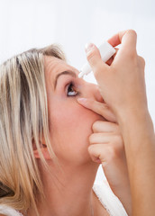Fototapeta premium Woman pouring drops in her eyes