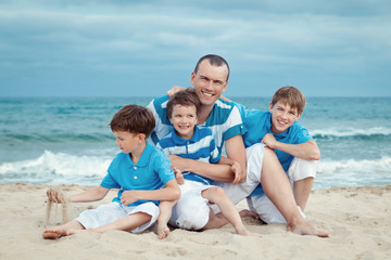 Father and sons sitting on sea