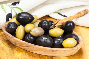 Olives in olive wood bowl with olive picker