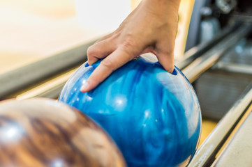 Holding ball against bowling alley.