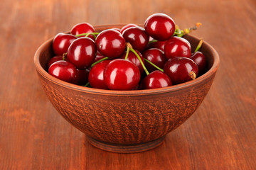 Cherry berries in bowl on wooden table close-up