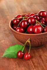 Cherry berries in bowl on wooden table close-up