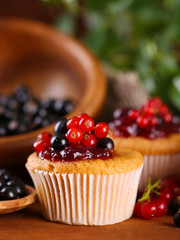 Tasty muffins with berries on wooden table