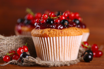 Tasty muffins with berries on wooden table
