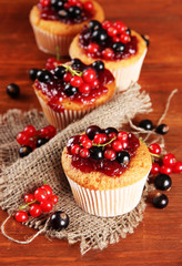 Tasty muffins with berries on wooden table
