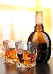Glass of liquor with bottle, on dark background