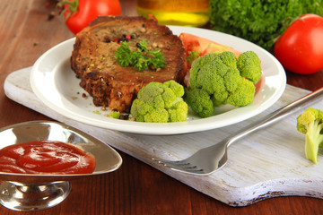 Piece of fried meat on plate on wooden table close-up