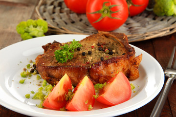 Piece of fried meat on plate on wooden table close-up
