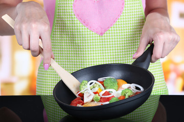 Hands cooking vegetable ragout in pan in kitchen