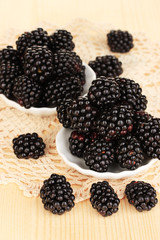 Sweet blackberry in bowls on wooden table