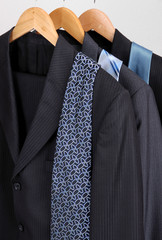 Suits and ties on hangers on gray background