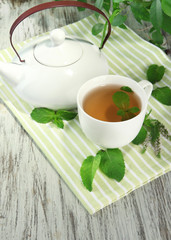 Teapot and cup of herbal tea with fresh mint flowers