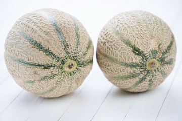 Two cantaloups on white wooden boards, studio shot