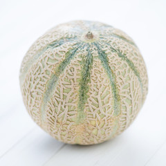 Rockmelon on white wooden background, close-up, studio shot