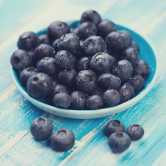 Saucer with ripe blueberries on wooden boards, close-up
