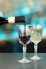Red wine being poured into wine glass, on bright background