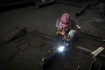 Skilled welder at work with sparks arcing.
