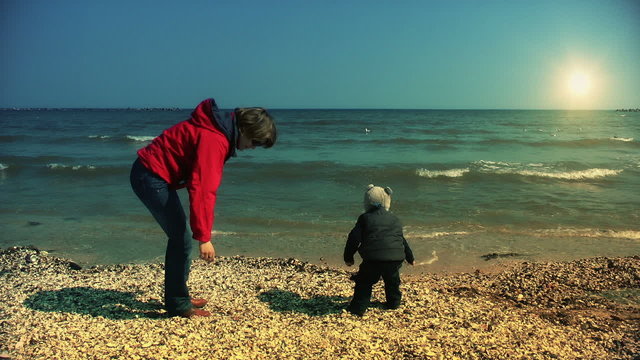 Mother and son throwing sea shells in water