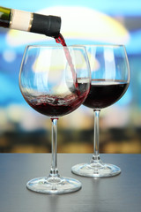 Red wine being poured into wine glass, on bright background