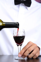 Bartender is pouring red wine into glass