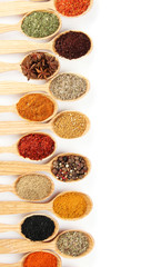 Assortment of spices in wooden spoons, isolated on white
