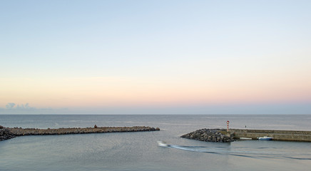 Obraz premium Boat leaving harbor at dawn in the Azores