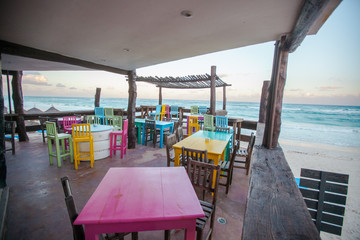 Fototapeta na wymiar Bright colored bar-restaurant on the white sandy beach in Tulum