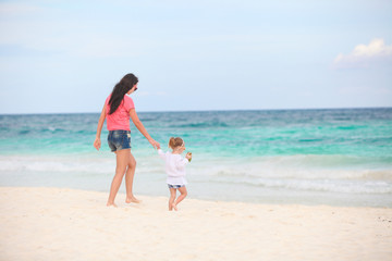 Young beautiful mother and her adorable little daughter running