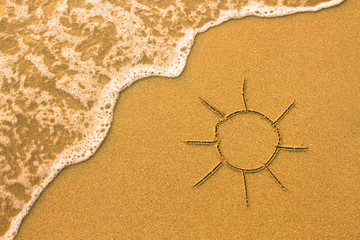 Sun drawn in the sand of a beach.