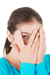 Fototapeta premium Shy teenage girl peeking through covered face