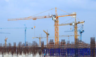 Construction site with multiple cranes on a blue background.