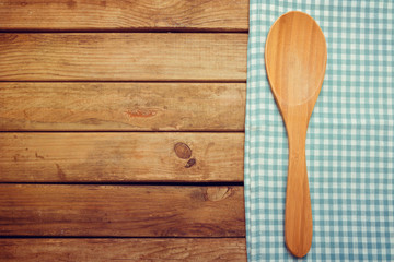 Wooden spoon and tablecloth over wooden background
