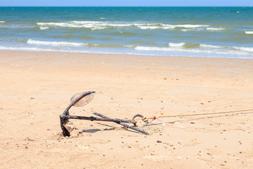 Small rusty traditional anchor on a beach by the sea