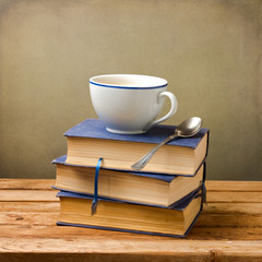 Old books and cup of coffee on wooden table