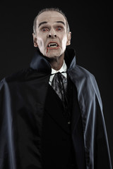 Obraz premium Dracula with black cape showing his scary teeth. Vamp fangs. Stu