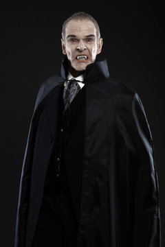 Dracula with black cape showing his scary teeth. Vamp fangs. Stu